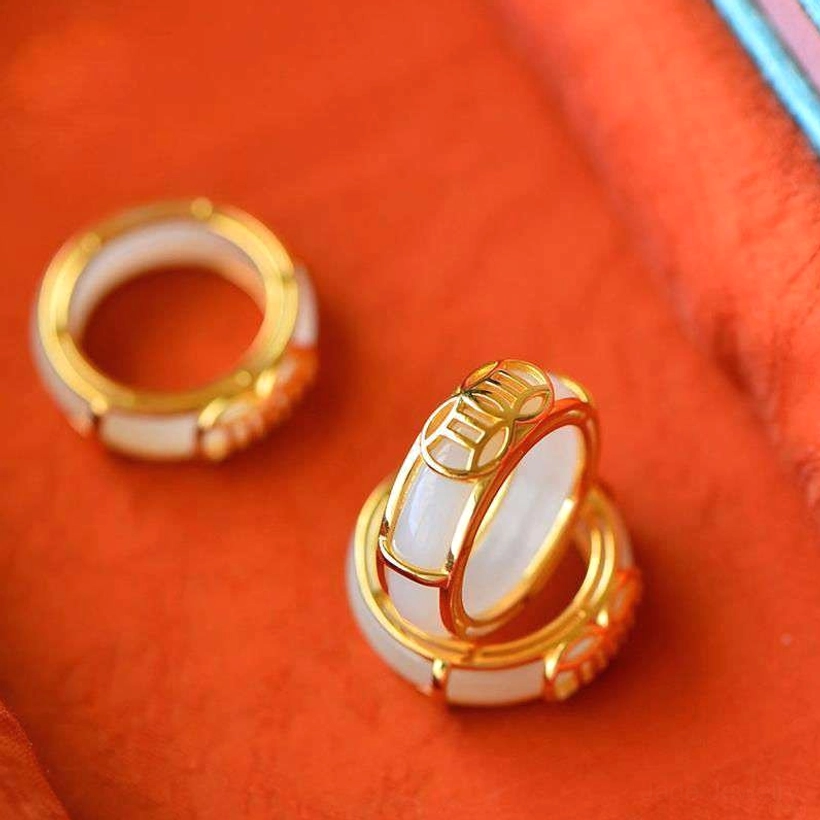 Two white jade lucky rings with different hollowed patterns stacked in flat lay, displaying ring collection