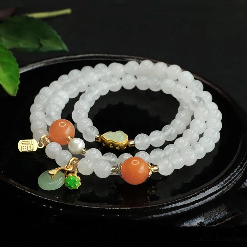 Three-quarter angle of double-layer white jade jade bracelet with green jade charm, gold Fu tag and gemstone accents