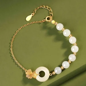 Top-down view of white jade peace buckle luck bracelet featuring adjustable gold spacer beads and jade charms