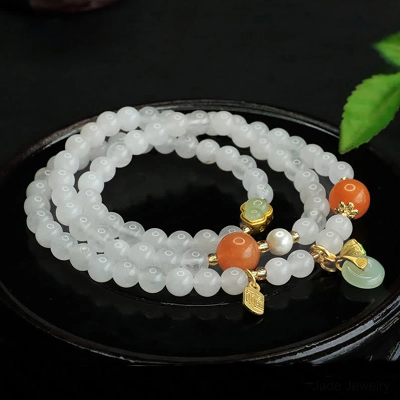 Overhead close-up of white jade peace buckle bracelet showing intricate beadwork with orange accents and jade charm details