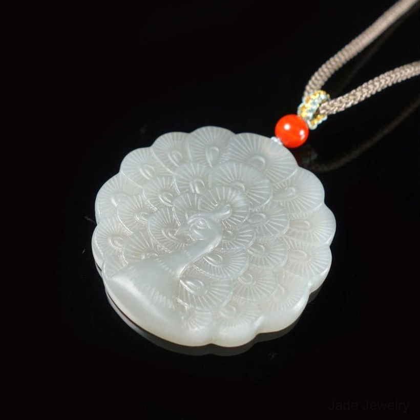 White jade peacock pendant necklace three-quarter front view displaying clear peacock feather carving details on scalloped round pendant