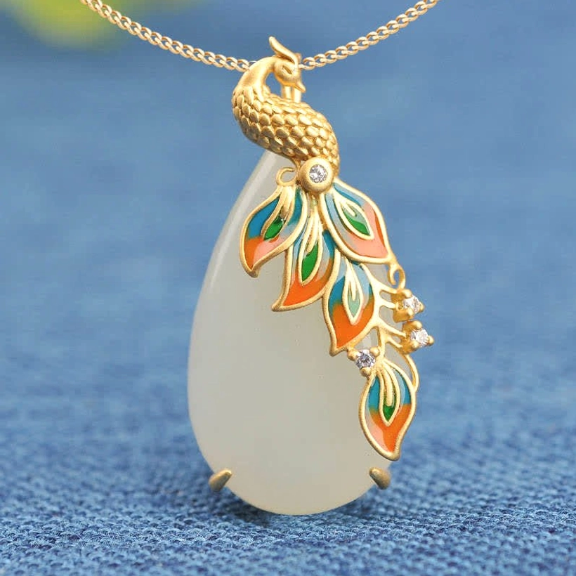Close-up front view of white jade peacock pendant, detailed enamel feather design with zircon inlays, gold metal clasp