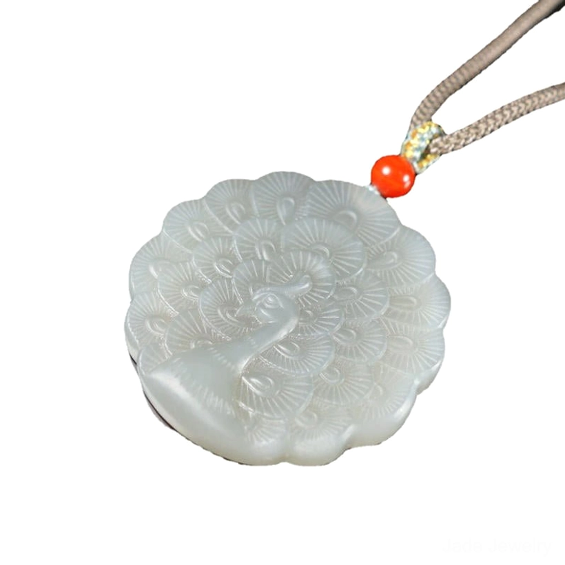 White jade peacock necklace low angle view highlighting intricate carved peacock head and full feather design on light grey jade with braided cord