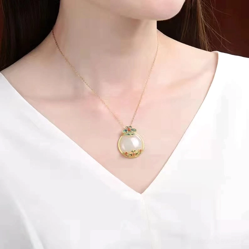 White jade flower pendant necklace worn by female model with white v-neck top, pendant positioned at collarbone, slim gold chain demonstrating everyday wearability, comfort, and elegant styling versatility