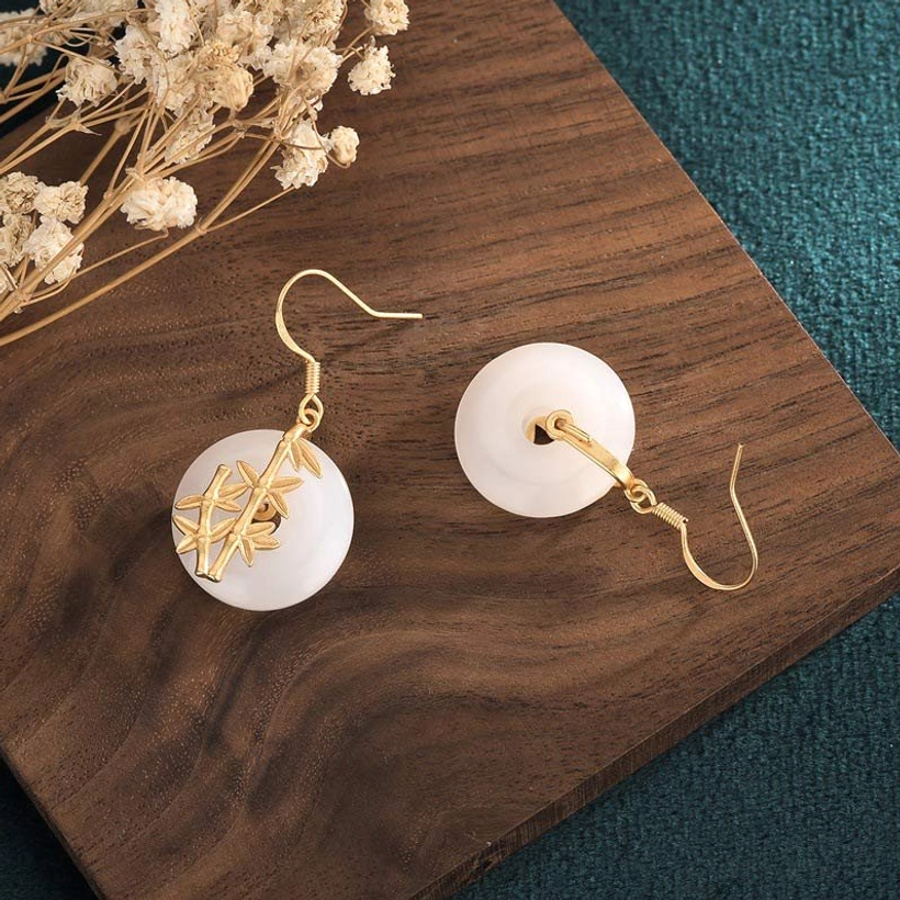 White jade earring pendant detail - reverse view showing jade craftsmanship on botanical backdrop