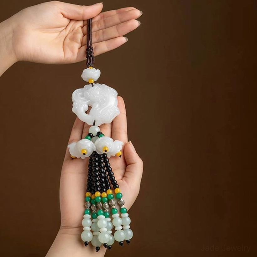 White jade Pixiu car pendant detailed front view held between hands, showing carved charm and beaded decoration