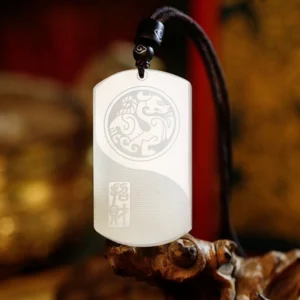 White jade Pixiu fortune pendant necklace front view with carved beast pattern and Chinese calligraphy on antique wooden backdrop