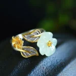 White jade plum blossom adjustable ring with 925 silver plating, top-down flat lay view showing delicate dual-tone flower design