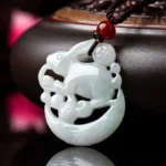 White jade rabbit crescent moon protection pendant necklace displayed on luxury wooden base with red agate accent bead