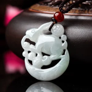 White jade rabbit crescent moon protection pendant necklace displayed on luxury wooden base with red agate accent bead