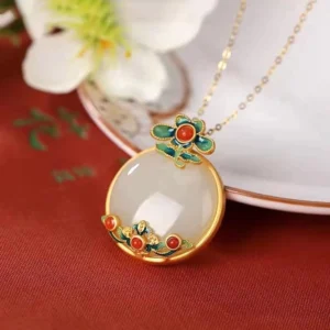 White jade red agate flower pendant necklace with cloisonné enamel details, three-quarter view showcasing intricate gold-plated bezel, hand-polished milky jade centerpiece, and delicate floral enamel work on red fabric background