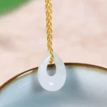 White jade teardrop pendant necklace with gold-plated chain, close-up view showing translucent stone