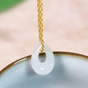 White jade teardrop pendant necklace with gold-plated chain, close-up view showing translucent stone