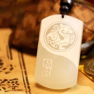 Overhead view of white jade Yin Yang pendant showing matte milky white finish and engraved circular mythical pattern design