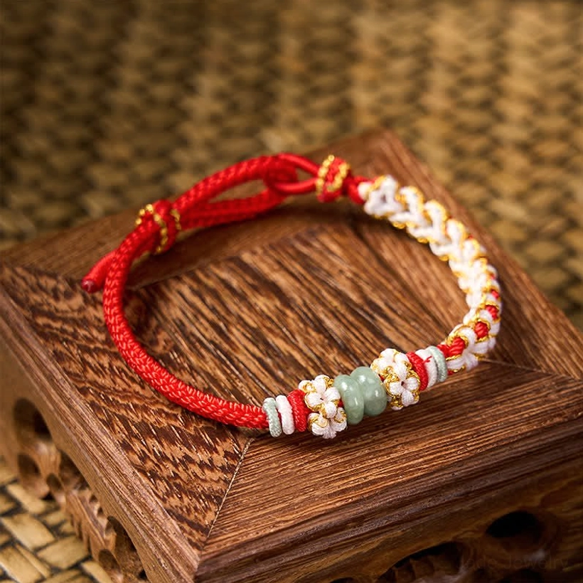 Woven peach blossom jade bracelet with red cord and polished jade beads top view