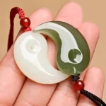 Yin Yang white jade and cyan jade pendant pair displayed on palm - handmade protection necklace