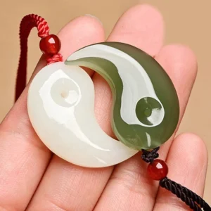 Yin Yang white jade and cyan jade pendant pair displayed on palm - handmade protection necklace