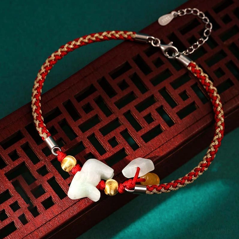 Zodiac jade bracelet with two carved jade pendants and red-gold mixed braided rope with silver metal clasp on dark green background