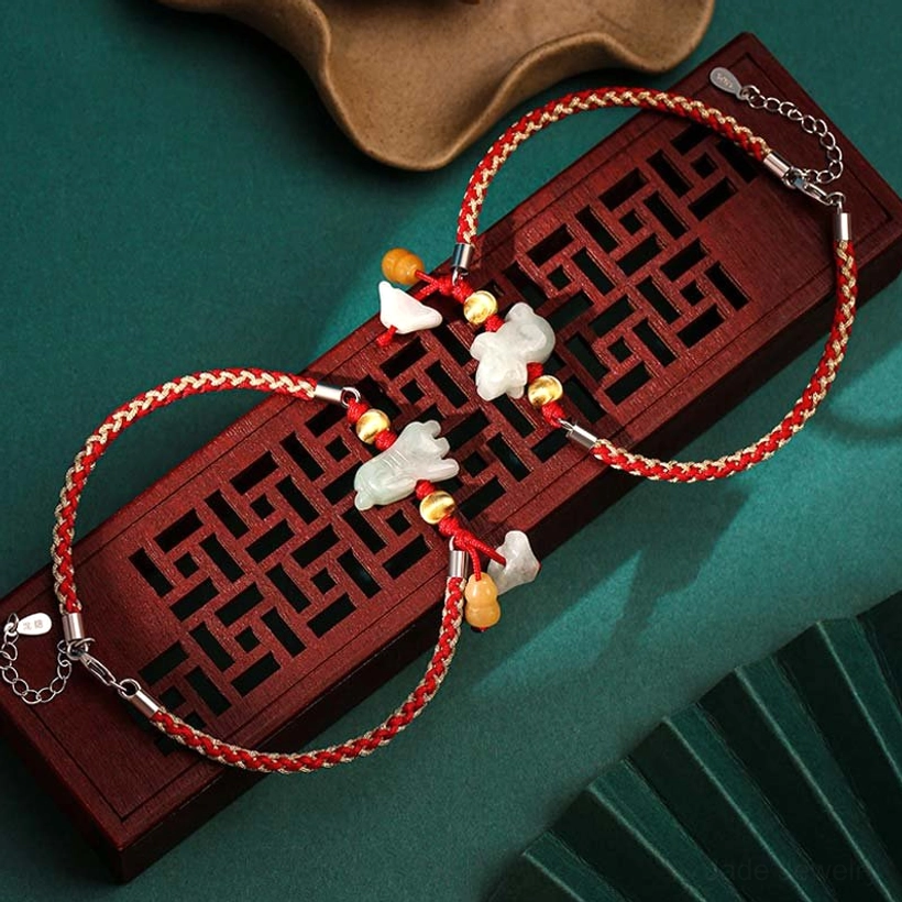 Chinese zodiac jade prosperity bracelet with red string on traditional wooden display tray, featuring carved jade animal charms and gold metal beads